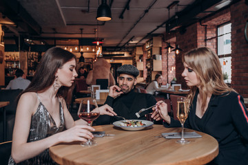 two beautiful young girls and a guy are sitting at a table in a restaurant