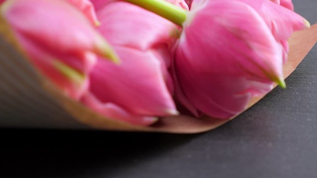 Pink tulips in kraft paper on black background. Rotate