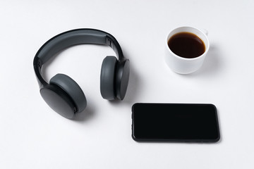 Headphones, smartphone and cup of coffee on white background. Copy space