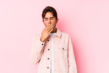 Young caucasian man posing in a pink background isolated yawning showing a tired gesture covering mouth with hand.