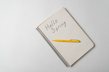 Hello spring handwriting notice. Top view of Notepad and pen on white background.