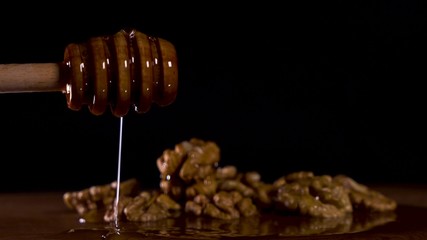 put honey spoon on wooden board where nuts are lay with delicious honey