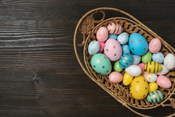 Basket full of colorful Easter eggs on wooden background. Happy Easter
