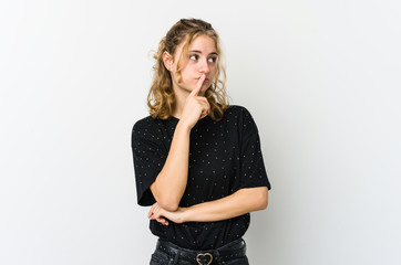 Young caucasian woman on white backrgound looking sideways with doubtful and skeptical expression.