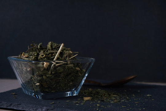 T&eacute; de ortiga en recipiente de cristal con cuchara de metal