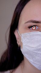 Woman with medical mask on her face. Close-up of woman's red eye. Concept of coronavirus epidemic or diseases.