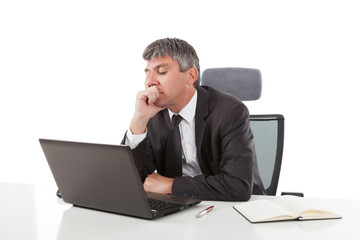 Gray haired casual looking businessman working on laptop computer