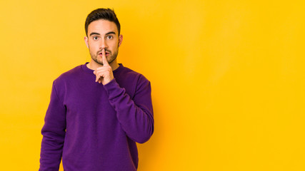 Fototapeta premium Young caucasian man isolated on yellow bakground keeping a secret or asking for silence.