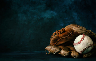 Baseball glove with ball close up in studio with dark texture backdrop, copy space for sport...