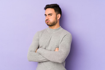 Young caucasian man isolated on purple background tired of a repetitive task.