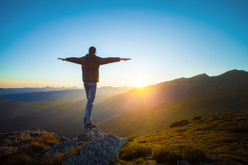 Man on the edge of the cliff, outstretched arms, feeling the freedom, mountain landscape