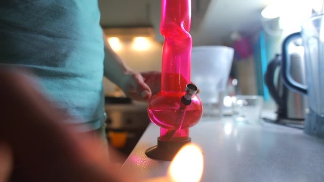 Closeup of bong smoking in the apartment kitchen. A man smokes medical marijuana. The concept of mental relaxation. Stress relief in self-isolation COVID-19. Mental and physical relaxation.