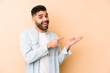 Young mixed race arabic man isolated excited holding a copy space on palm.
