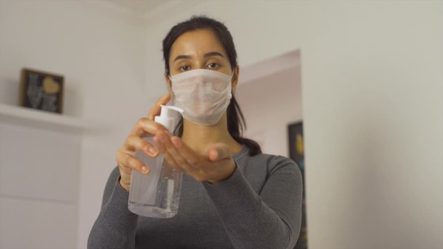 woman wearing white mask shows hand sanitizer to prevent coronavirus