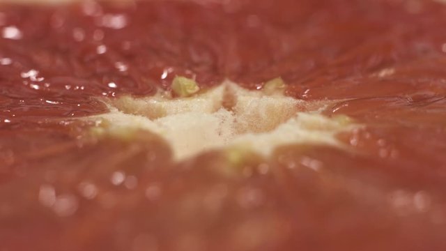 Close up macro shot of rotating grapefruit on the table. Extreme close up footage of spinning fruit.