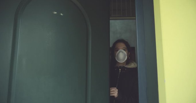 young woman wears mask to protect herself from covid-19 before leaving home. shot in slow motion