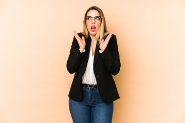 Middle age business woman isolated on beige background surprised and shocked.