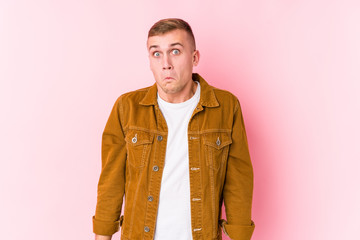 Young caucasian man isolated shrugs shoulders and open eyes confused.