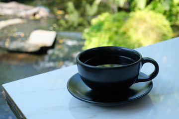 Black cup of hot coffee on table