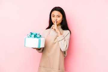 Young chinese woman holding a cake isolated showing number two with fingers.