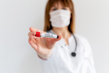 Test tube in female hand close up, woman in medical mask holding blood sample, vaccination, coronavirus outbreak, medical and chemical research, doctor or scientist, Covid-19, Sars