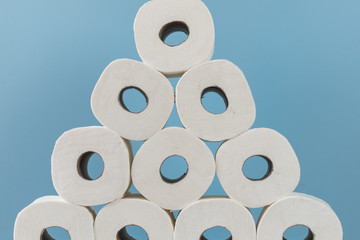 Rolls of toilet paper stacked up high against blue background