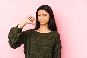 Young chinese woman isolated on a pink background showing a dislike gesture, thumbs down....