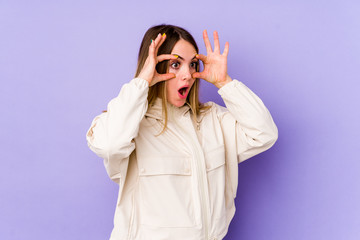 Young caucasian woman isolated on purple background keeping eyes opened to find a success opportunity.