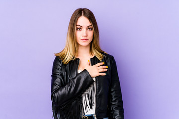 Young caucasian woman isolated on purple background taking an oath, putting hand on chest.