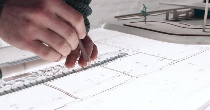 Close up of Man&rsquo;s hands drawing lines on the Large Format Paper at Modern Office. Architect using Ruler and Pencil to make Blueprints on the Paper. Having very Responsible Job. Great work.
