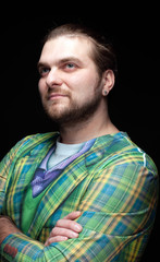 handsome stylish man in green blazer with crossed arms and looking away isolated on black