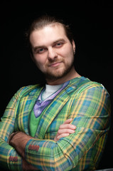 handsome stylish man in green blazer with crossed arms and looking at camera isolated on black