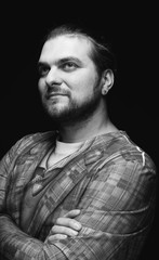black and white image of handsome stylish man in blazer with crossed arms and looking away isolated on black