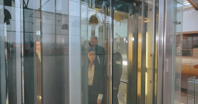 Business people coming out of glass elevator in office building