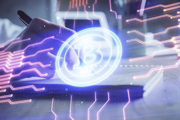 Cryptocurrency hologram, bitcoin, ico theme over hands taking notes background. Concept of...