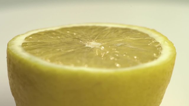 Close up footage of rotating fresh yellow half lemon on white table.