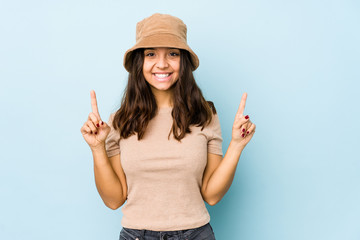 Young mixed race hispanic woman isolated indicates with both fore fingers up showing a blank space.