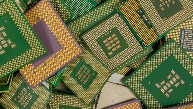 Panning across an assorted pile of CPUs. They were removed from computers for recycling. The pins on most of them are gold plated.