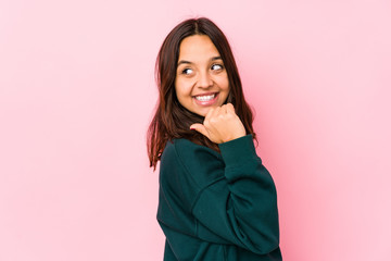 Young mixed race hispanic woman isolated points with thumb finger away, laughing and carefree.