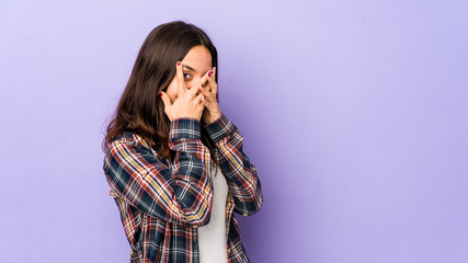 Young mixed race hispanic woman isolated blink through fingers frightened and nervous.