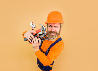 Repairment tools. Industrial worker. Repair. Smiling worker holds repair tools. Building. Industry. Technology. Spanner. Bearded builder. Builder in construction helmet. Hard hat. Hammer. Screwdriver.