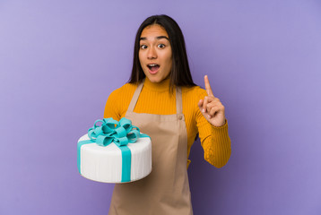 Young asian woman holding a cake isolated having an idea, inspiration concept.