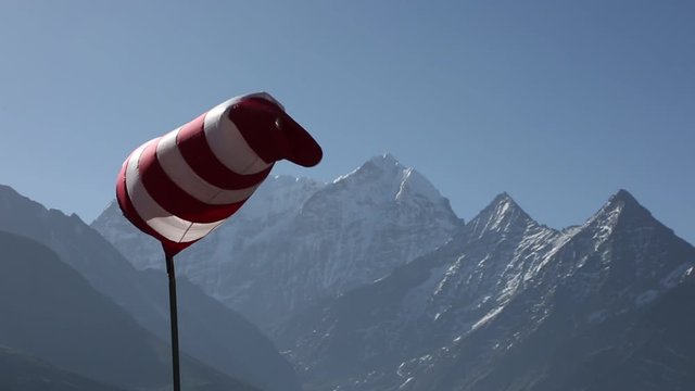 Windsock blowing in wind with Himalaya Mountain peaks in background
