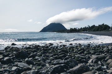 cerro con una nube exotica y piedras con mar