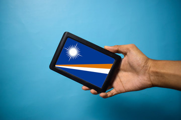 Man holding Smartphone with Flag of Marshall islands. Marshall Islands Flag on Mobile Screen isolated On Blue Background