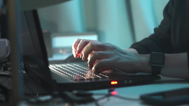 close up footage of hands of hacker girl who is typing on computer. woman sits at night on computer and tries to hack into system. Crime scene.
