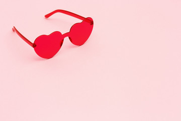Minimal style fashion photography with heart shaped red glasses on pink paper background. Pink...
