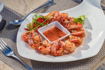 Shrimps starters with orange sauce and lime on a white plate