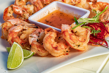 Shrimps starters with orange sauce and lime on a white plate