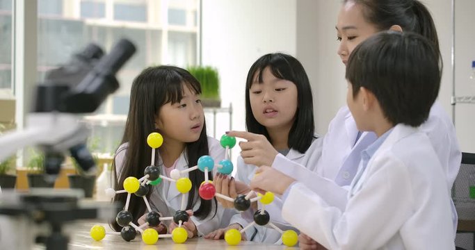 Teacher Using Molecular Model Kit Teaching Children Chemical Experiments in Classroom Laboratory. People with science and education concept.
